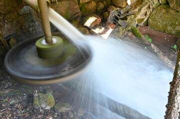 Long exposure of water falling on mill wheel. Watermill in nature for grinding grain.