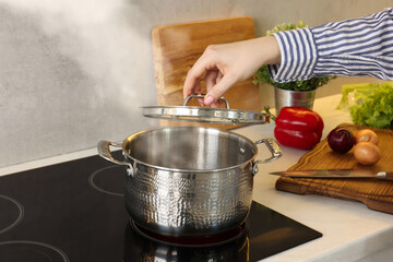 Woman cooking dinner on cooktop in kitchen, closeup