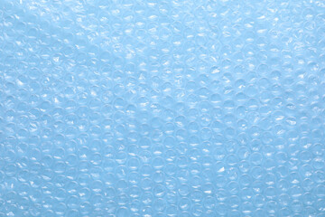 Transparent bubble wrap on light blue background, top view