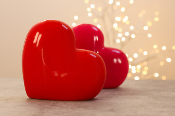 Ceramic hearts on grey table against blurred lights, space for text