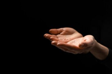 Religion. Woman with open palms praying on black background, closeup. Space for text