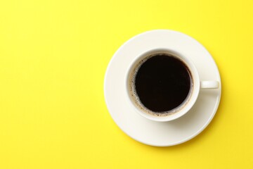 Cup of aromatic coffee on yellow background, top view. Space for text