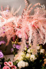 Close-up of sprigs of artificial pink fern in a vase with other flowers