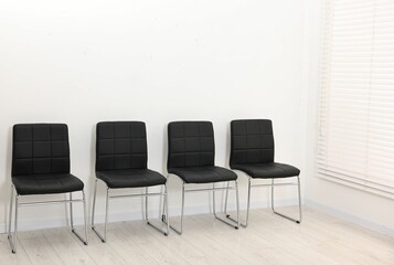 Many chairs near white wall in waiting area indoors
