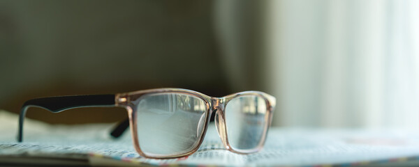 Eyeglasses resting on open newspaper in soft indoor light, concept of daily reading ritual