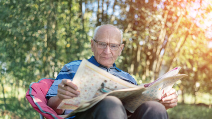 Senior man engrossed in newspaper relaxed amidst lush garden greenery. Morning read in tranquil natural surroundings