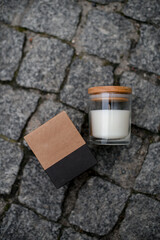 Soy-scented candle in a glass jar and a cardboard box from it lie on the pavement paved - 790746759