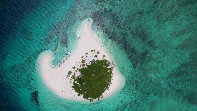 4K Aerial Drone video of Patawan Island with beautiful white sand and turquoise blue water. Boats anchored on the beach with palm trees in the middle. Balabac, Philippines