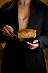 Female hands hold a spatula with a piece of cake in front of her