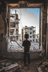 A child looking out of the window at destroyed buildings. War concept