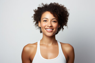 Smiling Young African American Woman with Afro Hair in White Tank Top on a Plain Background