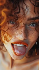 Fototapeta premium Close-up portrait of a cut-up girl with curled hair and freckles, showing tongue