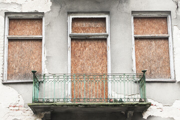 Tenement building balcony. Brick wall cracked facade. Old architecture. Abandoned apartment. Grunge forsaken building. Destroyed building OSB board cover.