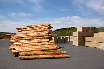 Pile of debarked tree trunks and stacks of timber beams at a sawmill in the Eifel forest in Europe