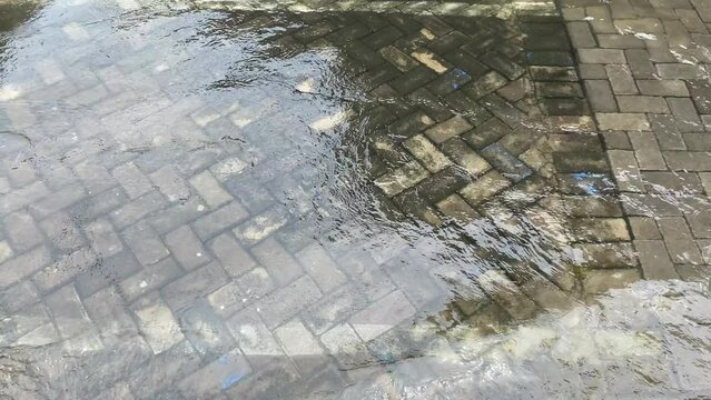 Top view or flat lay view of shallow water flow on grey paved background, flood on the street