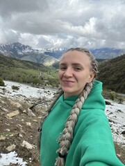 A woman on the background of the Ceylomsky pass in Ingushetia. A trip uphill to the Tsei Lum pass on a cloudy spring day. Panorama of the high cliffs of the Dzheyrakh gorge