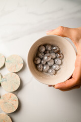 Woman's hand holds a ceramic bowl with nuts sprinkled with silver paint