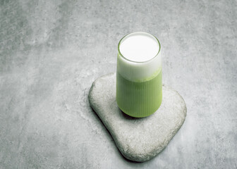 Matcha latte green tea with milk foam in tall glass isolated on grey background, copy space.