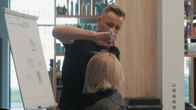 Stylist giving a final touch to a blonde bob haircut in a modern salon