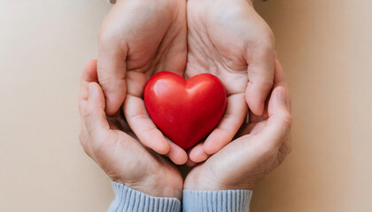 Father and son’s hands cradle a glossy red heart against a soft pastel backdrop, symbolizing familial love.