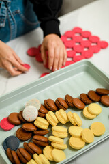 White plastic container is filled with colorful macaroon halves, on a blurred background