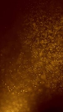 Blurred bokeh background of gold dust particles slowly floating in the air. Golden particles float in the air, magic background. Vertical shot