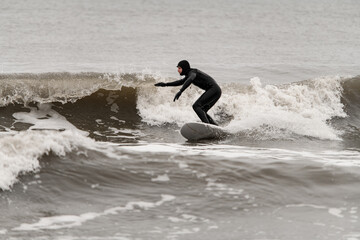 Male surfer riding a surfboard on a high wave, keeping his balance - 790780122