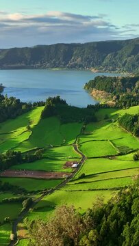 Azores nature on sunny day. Aerial shot of green meadows, mountains and Furnas lake on Sao Miguel Island, Azores, Portugal. Vertical Screen 