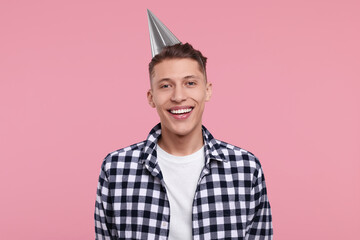 Happy man in party hat on pink background