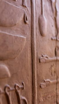Close shot of Egyptian hieroglyphs on the wall in Hatshepsut temple. Antique stone wall with carved ancient Egyptian hieroglyphs. Shallow DOF, Vertical Screen