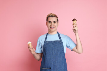 Portrait of happy confectioner holding ice cream cones on pink background