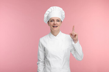 Happy chef in uniform pointing at something on pink background