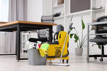 Cleaning service. Mop, bucket with supplies and wet floor sign in office