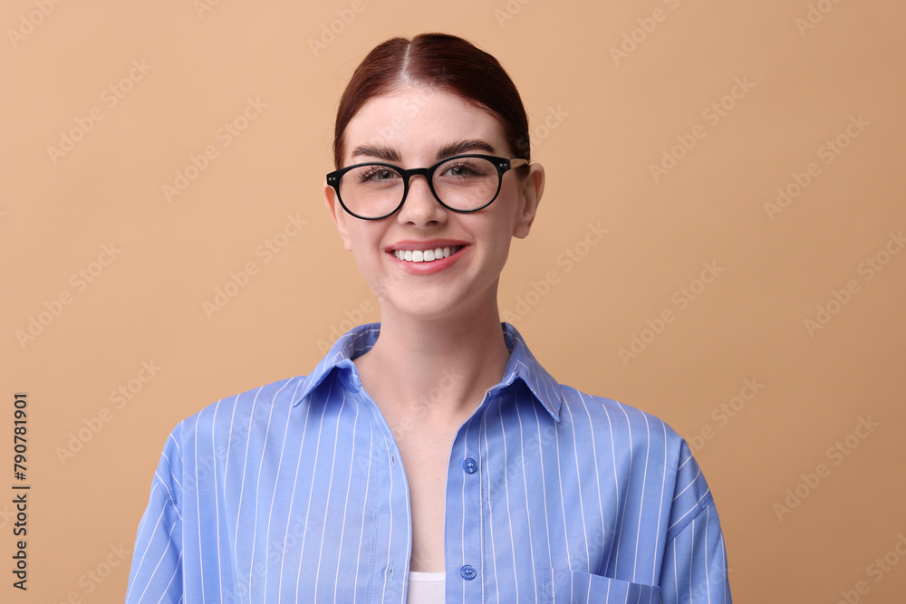 Wall mural Portrait of smiling woman in glasses on beige background