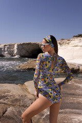 beautiful sensual woman with dark hair in elegant printed beach clothes posing in the white rock beach on Cyprus