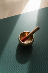 Singing meditation bowl on a yoga mat, ray of sunlight shines on a yoga mat, copy space.