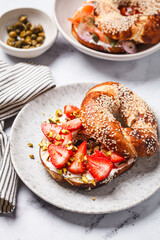Bagel with cream cheese, strawberries and pistachio for breakfast.