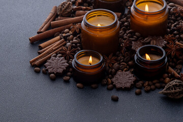 Soy scented candle in a jar. Coffee beans, anise, cinnamon spices. The candles are burning. Dark...