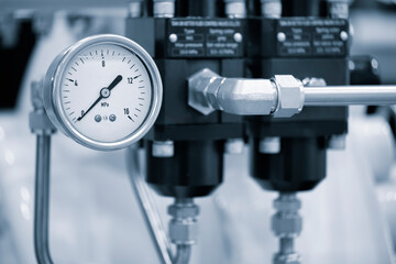 A black and silver pressure gauge is attached to a pipe. The gauge is set at a pressure of 16 Mpa