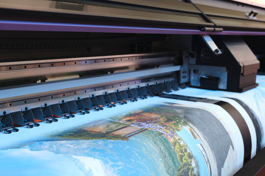A printer is printing a picture,  printer is black and silver. The image is blurry