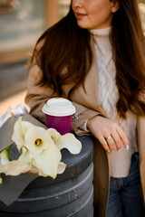 Focus on a bouquet of white lilies and a cup of coffee on a concrete stand