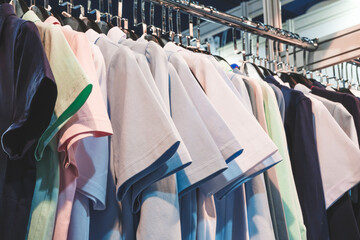 A rack of clothes with a variety of colors and styles. The clothes are hanging on hangers and are neatly arranged. Concept of organization and orderliness
