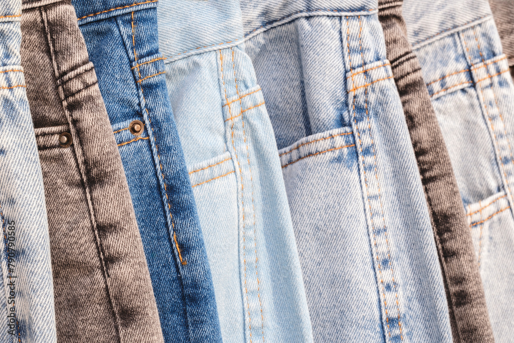 Leinwandbilder a row of jeans with different colors and patterns. the jeans are hanging on a rack