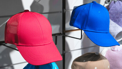 Two hats, one red and one blue, are displayed on a rack. The red hat is on the left and the blue hat is on the right