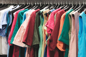 A rack of clothes with a variety of colors and styles. The clothes are hanging on hangers and are organized by color. Concept of variety and abundance, as there are many different types of shirts