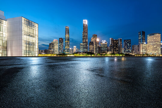 Asphalt road with modern city buildings scenery at night. Road ground after rain.