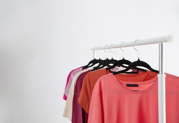 row of t-shirts on a hanger against a background of a white wall hanger