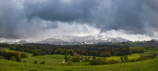 Ein typischer Tag im April am Rande der Alpen - Schnee in den Bergen und grüne Landschaften im Tal