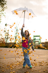 Cute smiling young woman standing on an asphalt path and holding an umbrella high above her head