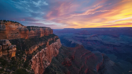 Mountain cliff edge overlooking epic canyon landscape at sunrise with beautiful colorful sky and clouds